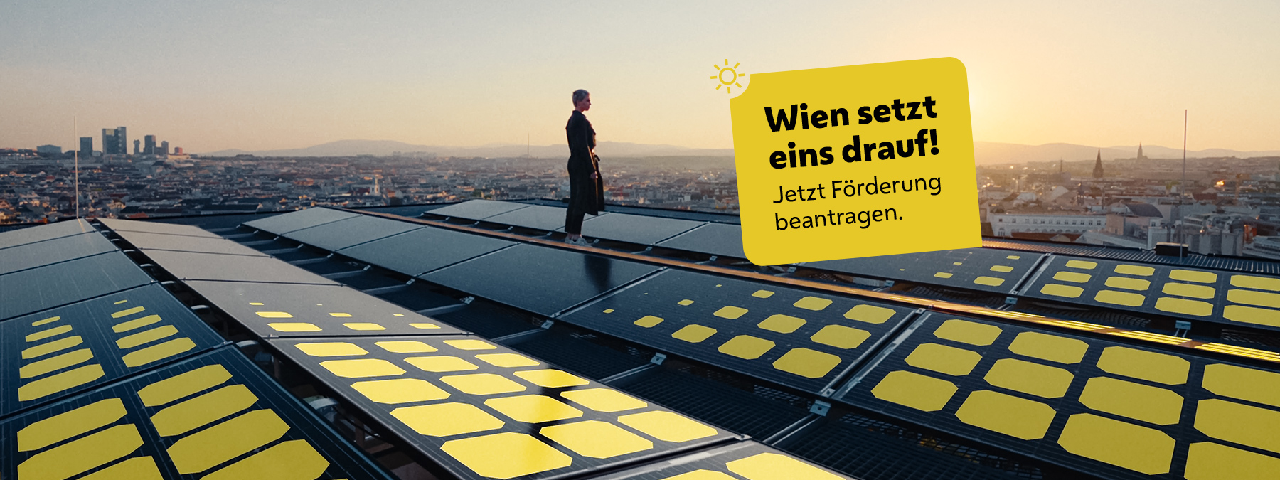 Frau steht auf Dach mit Solarpanelen mit Blick über Wien